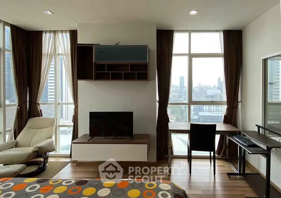 Modern living room with city view, featuring stylish furniture and large windows for natural light.