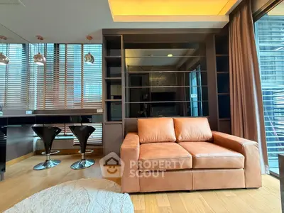 Modern living room with leather sofa and stylish kitchen area in luxury apartment.