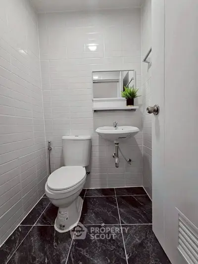Modern minimalist bathroom with sleek white tiles and compact fixtures.