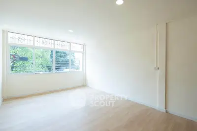 Spacious empty room with large windows and wooden flooring, perfect for customization.