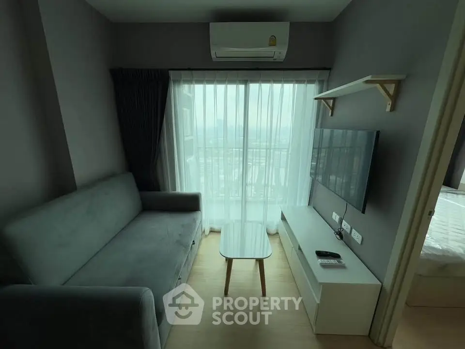 Modern living room with sleek furniture and large window offering natural light.