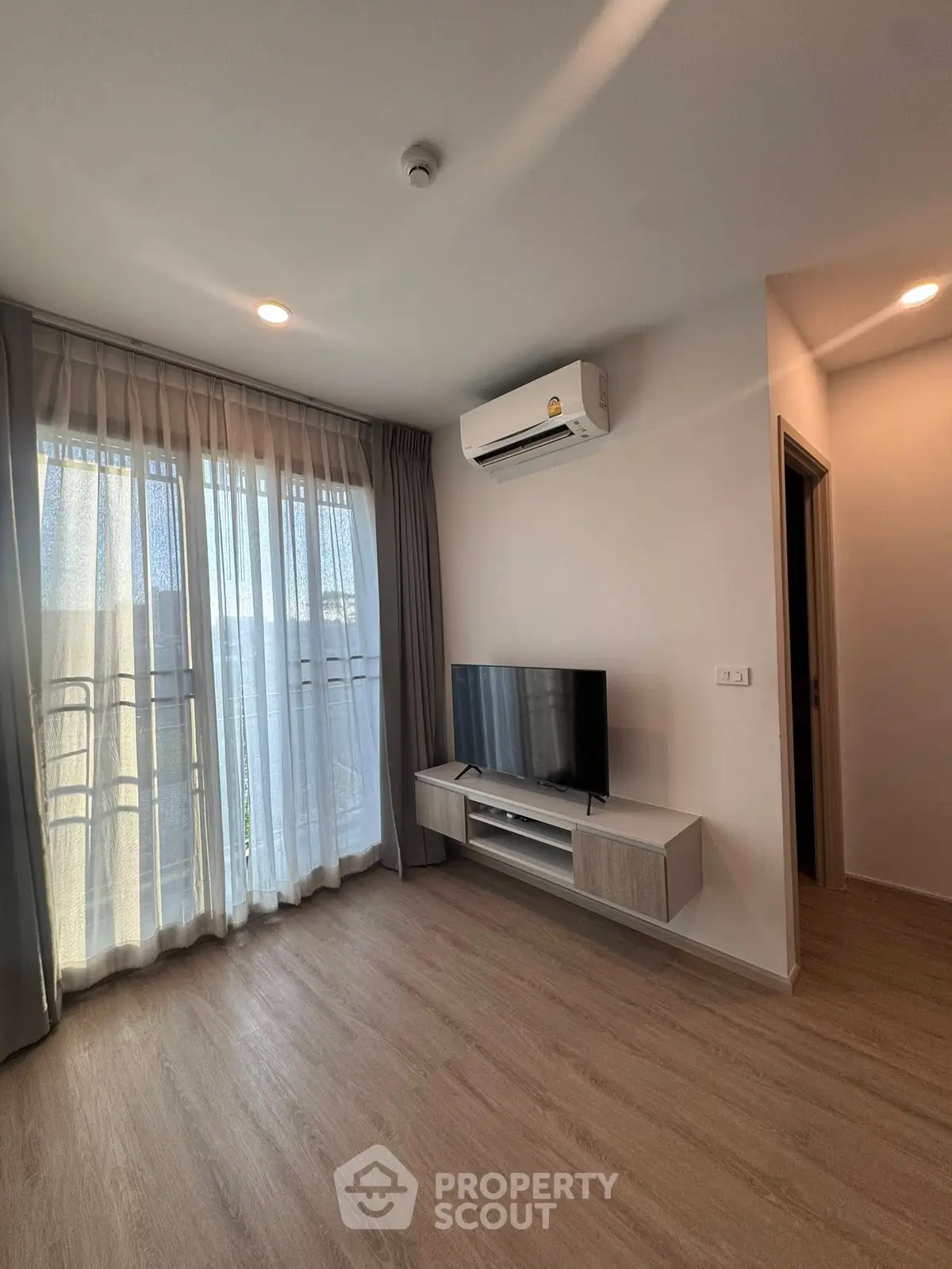 Modern living room with sleek TV setup and natural light from large windows.