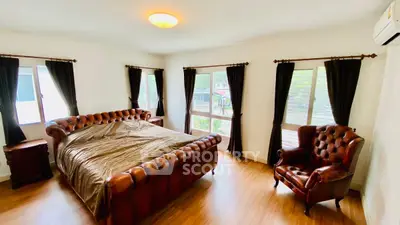Spacious bedroom with elegant leather furniture and large windows for natural light.
