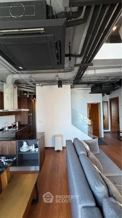 Modern industrial-style living room with open kitchen and sleek design elements.