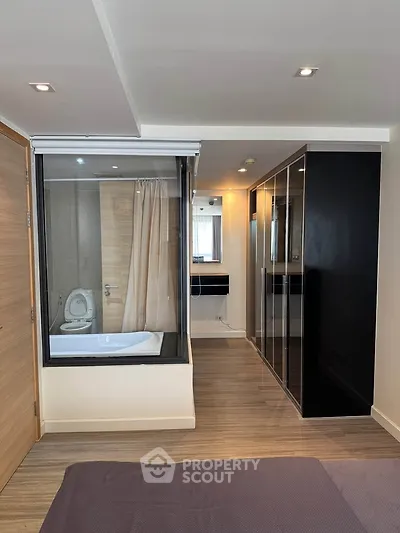 Modern bedroom with glass-enclosed bathtub and sleek wardrobe design