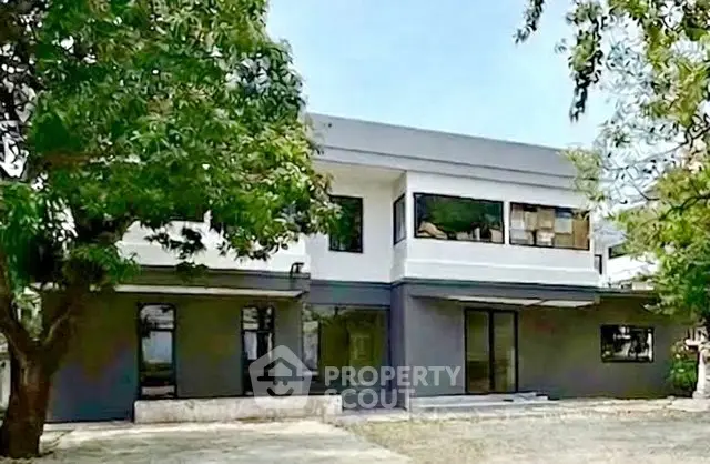 Modern two-story building with large windows and surrounding greenery.