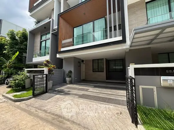 Modern townhouse exterior with sleek design and spacious driveway in a serene neighborhood.