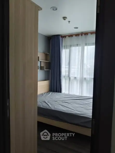 Cozy bedroom with large window and modern furnishings in urban apartment