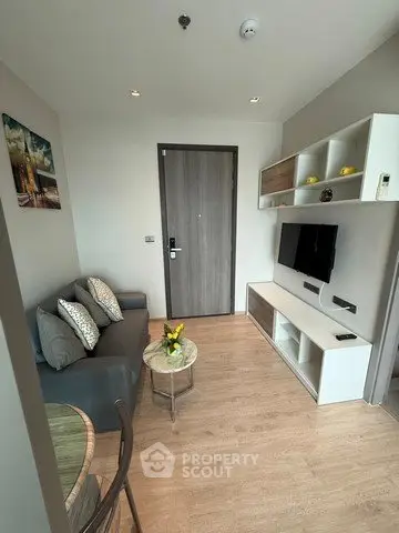 Modern living room with sleek furniture and wall-mounted TV in a cozy apartment.