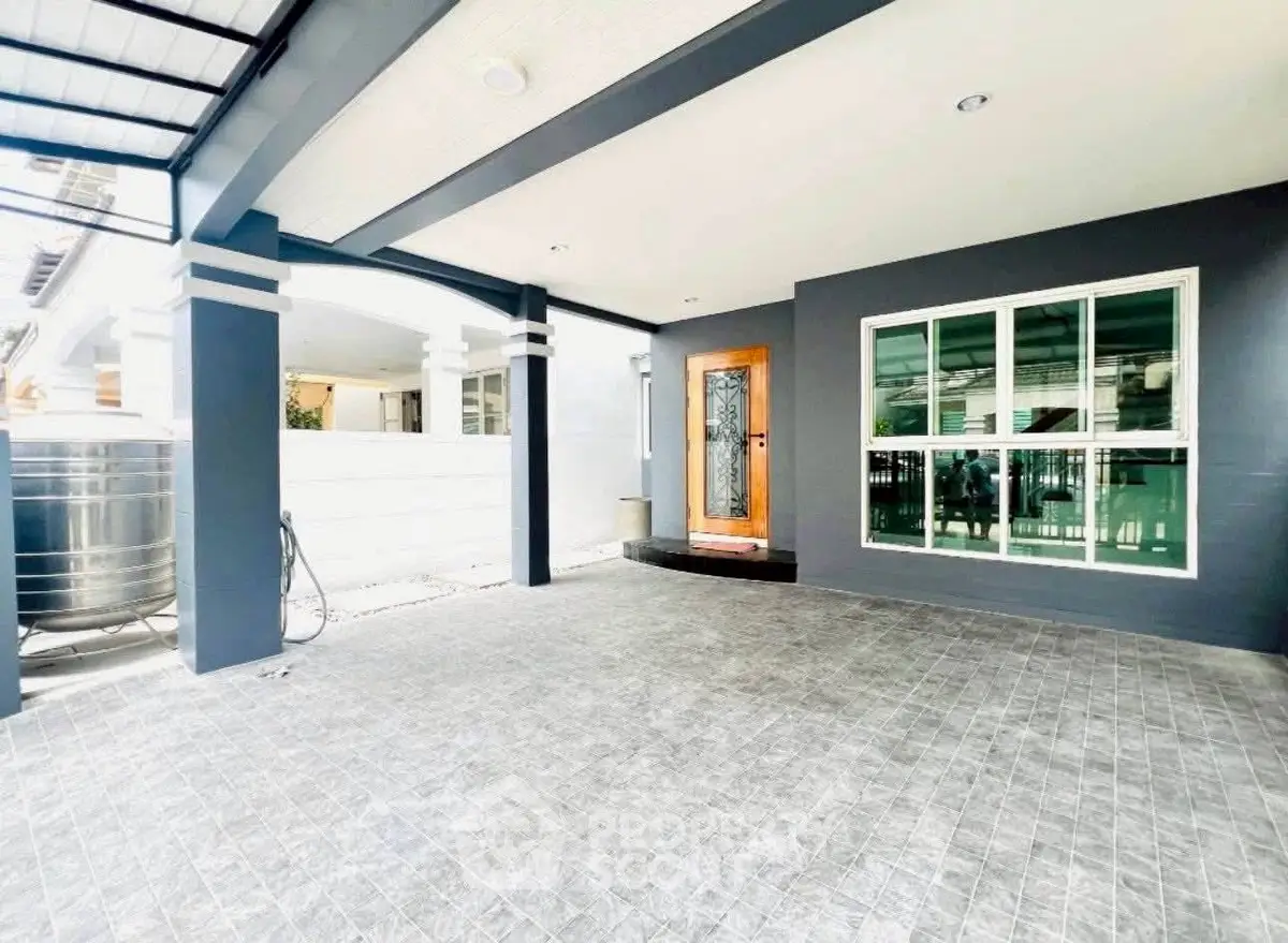 Spacious modern home entrance with covered patio and stylish door