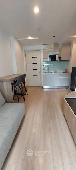 Modern apartment interior with open kitchen and cozy living area, featuring sleek design and contemporary furnishings.