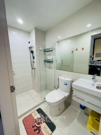 Modern bathroom with glass shower, white tiles, and sleek fixtures