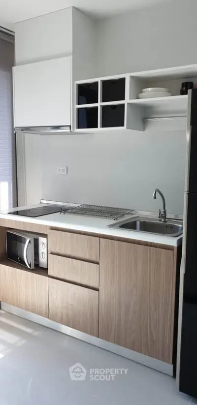 Modern kitchen with sleek cabinetry and built-in microwave in a compact layout.