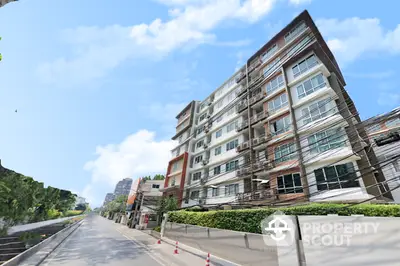 Modern urban apartment building with lush greenery and clear blue sky