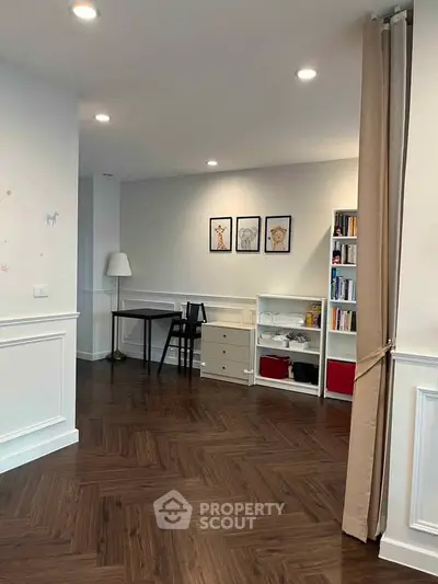 Spacious study area with elegant wood flooring and ample storage