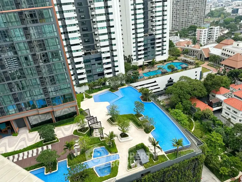 Stunning aerial view of luxury apartment complex with multiple swimming pools and lush greenery.