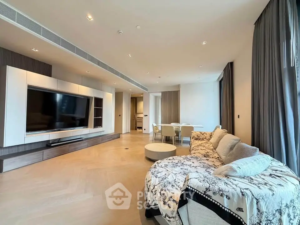 Spacious modern living room with elegant decor and large TV, perfect for relaxation and entertainment.
