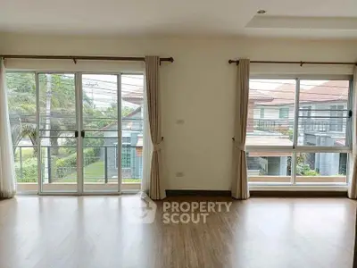 Spacious living room with large windows and wooden flooring in modern home.