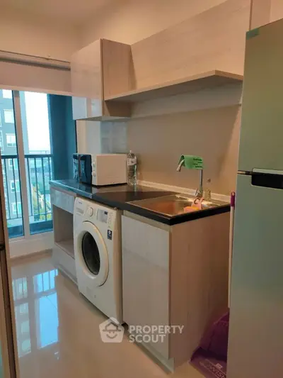 Modern kitchen with washing machine and sleek cabinetry in a high-rise apartment.
