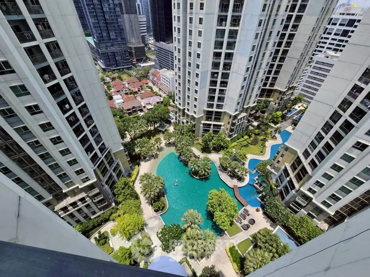 Stunning aerial view of luxury high-rise buildings with lush pool area in vibrant urban setting.