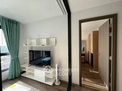 Modern living room with TV and stylish shelving, featuring a glimpse into a cozy bedroom.