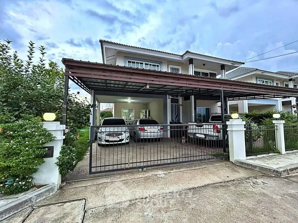 Spacious two-story house with covered parking for multiple cars and lush greenery.
