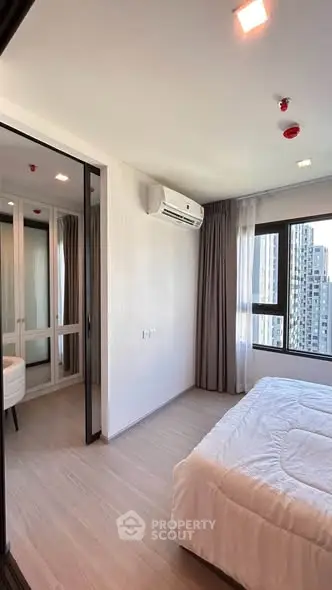 Modern bedroom with large window and city view, featuring sleek design and ample natural light.