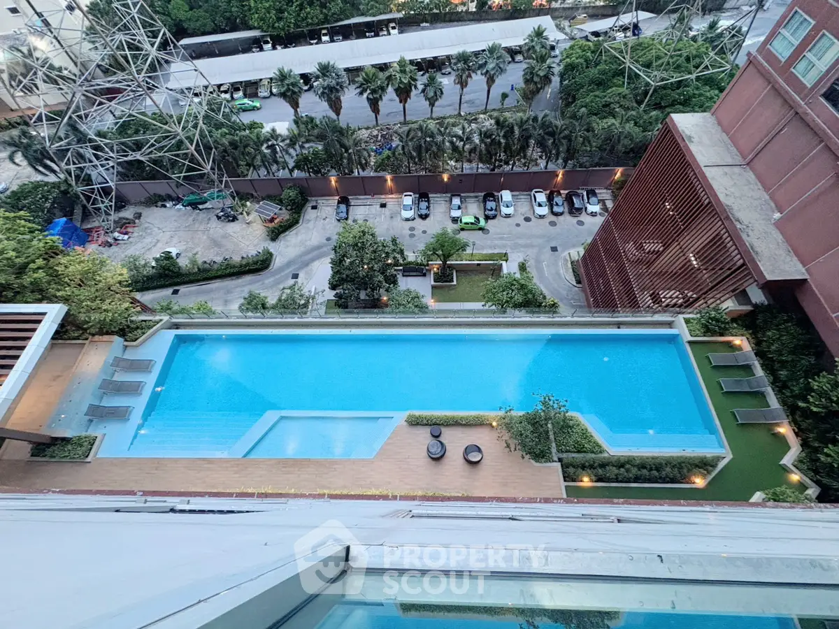 Stunning aerial view of modern apartment pool with lush greenery and cityscape backdrop.