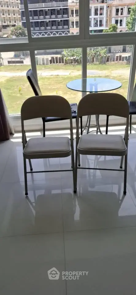 Bright apartment with large windows offering a stunning view, featuring a modern dining area with sleek chairs.