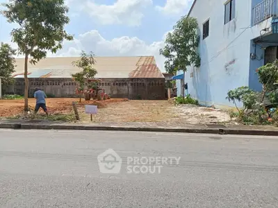 Vacant land plot with potential for development, featuring a clear sky and adjacent building.
