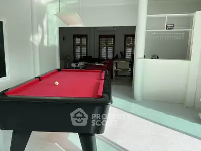 Spacious living area with red pool table and modern decor