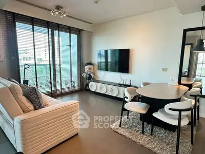 Modern living room with stylish furniture and large TV, featuring floor-to-ceiling windows and chic decor.