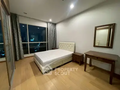 Spacious bedroom with wooden flooring and large window offering city views.