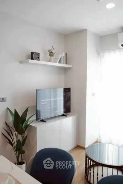 Modern living room with sleek TV setup and stylish decor in bright apartment.