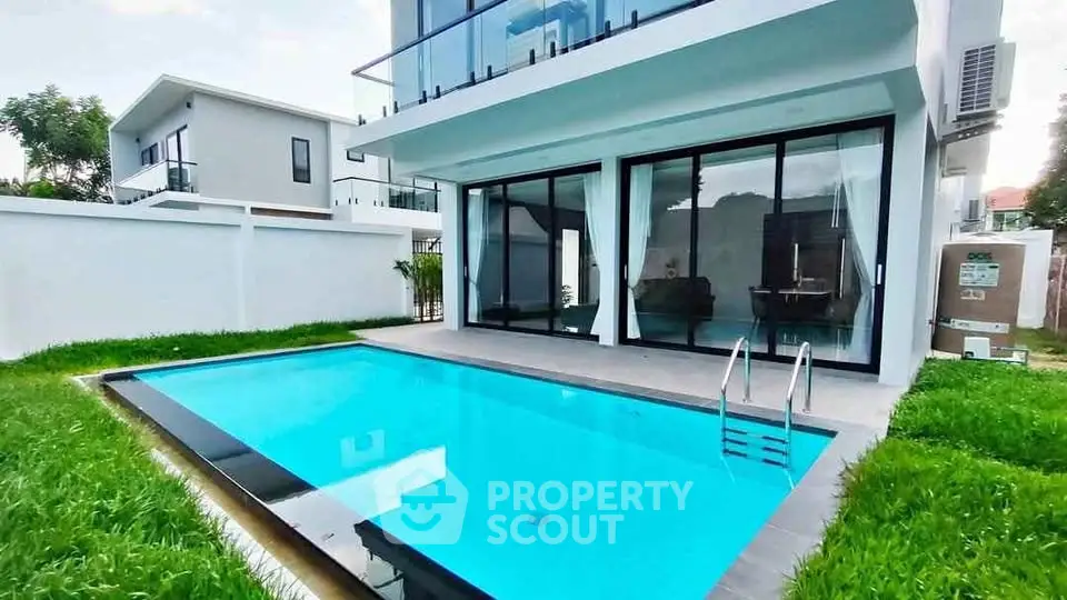 Modern villa with private pool and glass facade, lush green lawn, and sleek architectural design.