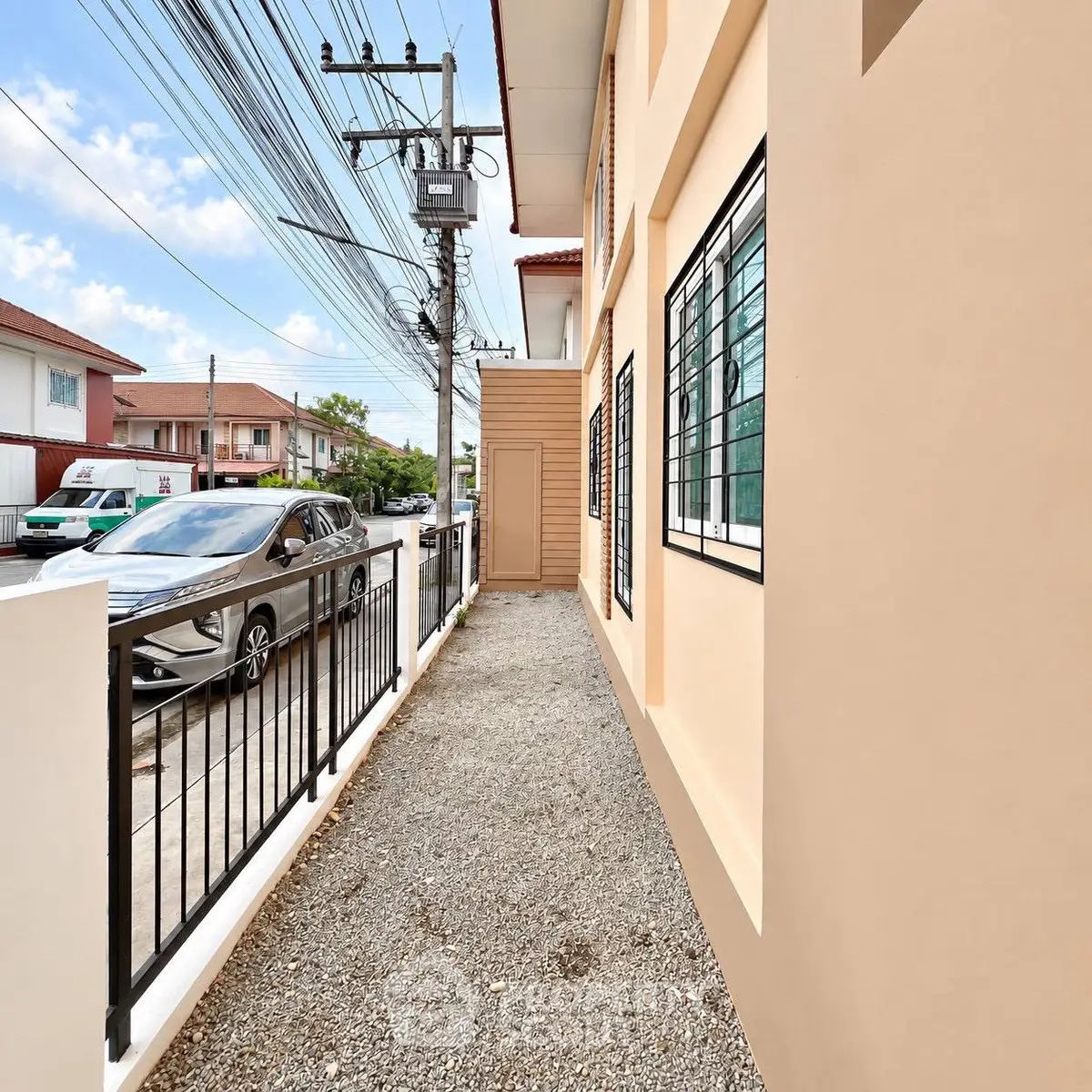 Charming residential exterior with gravel path and modern railing, perfect for urban living.