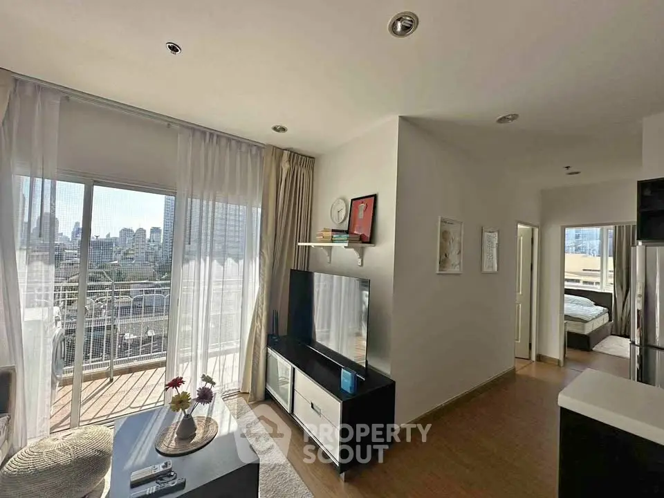 Modern living room with balcony and city view, featuring sleek furniture and natural light.