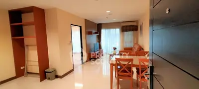 Spacious living room with dining area in modern apartment, featuring elegant furniture and natural light.