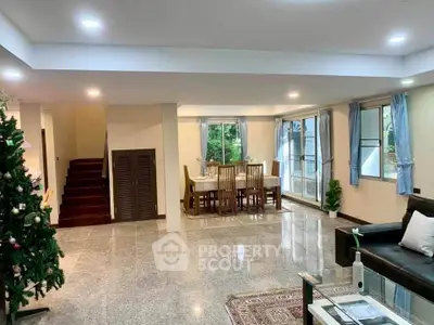 Spacious living room with dining area and Christmas tree, featuring large windows and modern decor.