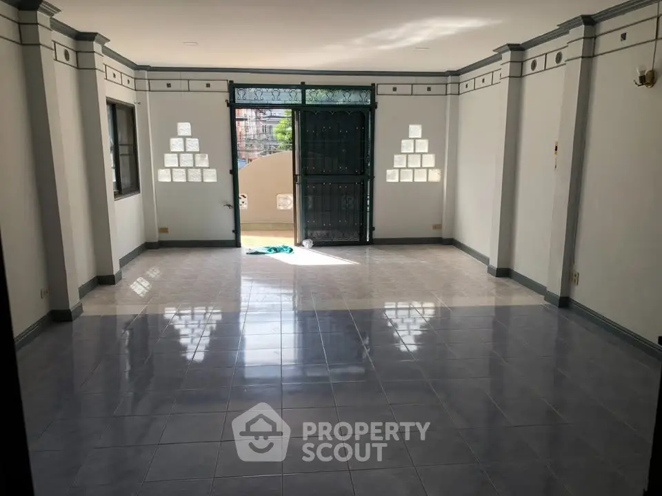 Spacious living room with large windows and glossy tiled floor, perfect for natural light lovers.
