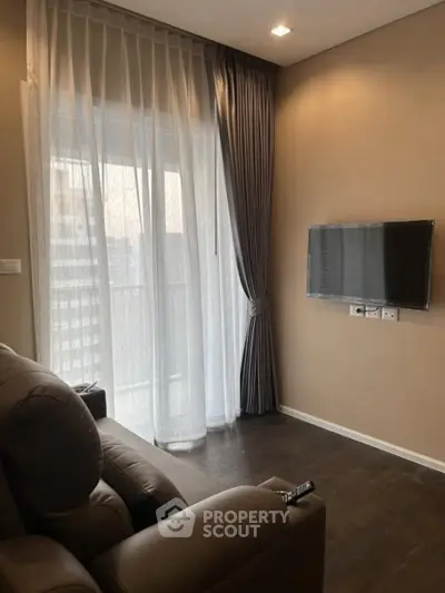 Cozy living room with modern decor and wall-mounted TV, featuring elegant curtains and comfortable seating.