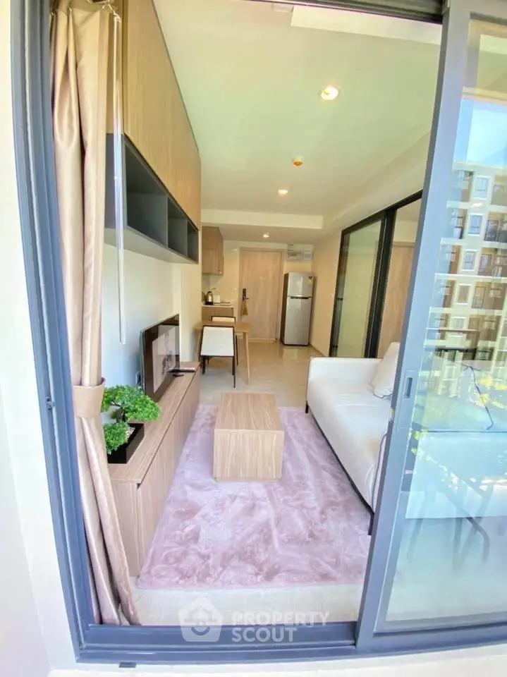 Modern living room with open layout and balcony view, featuring sleek furniture and natural light.