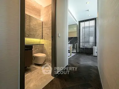 Modern apartment hallway leading to a stylish bathroom and living area.