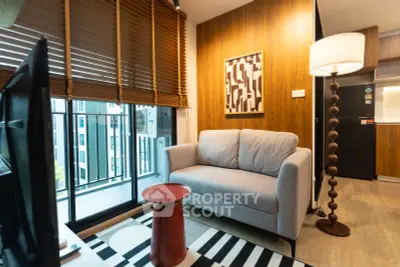 Modern living room with cozy sofa, stylish lamp, and balcony view in urban apartment.