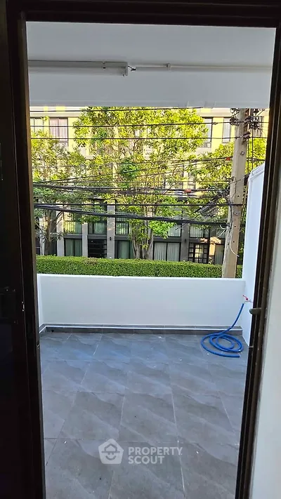 Spacious balcony with modern tiles and lush green view, perfect for relaxation.
