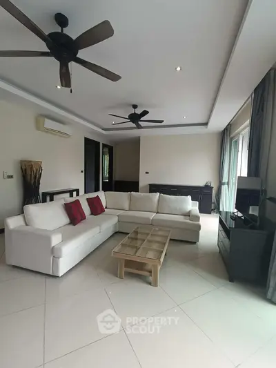 Spacious living room with modern furniture and ceiling fans in a bright, airy setting.
