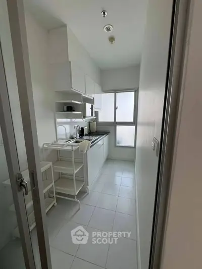 Compact modern kitchen with sleek white cabinetry and natural light
