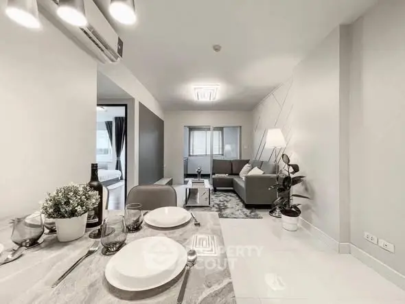 Modern open-plan living room with dining area, featuring sleek furniture and contemporary decor.