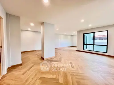 Spacious modern living room with elegant wooden flooring and large windows.