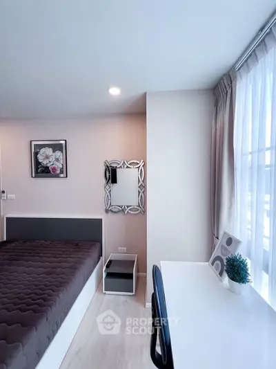 Modern bedroom with stylish decor and natural light, featuring a comfortable bed and workspace.